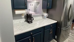 A kitchen with dark cabinets, a stainless steel refrigerator, a coffee maker, and a marble countertop. - Downtown Harrisburg close to Hershey PA-Sleeps 8 (Harrisburg)