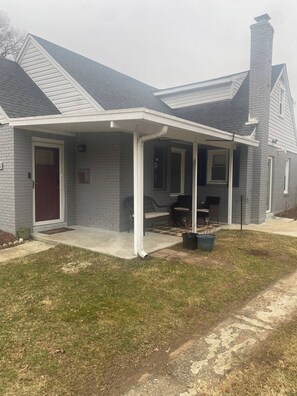 A residential house with a covered porch, a brick chimney, and a front door. - Pet-Friendly Family Home Near DC | Sleeps 16 (Hyattsville)