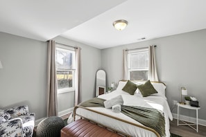 A bedroom with a bed, bedside tables, a mirror, and a window with curtains. - Pet-Friendly Family Home Near DC | Sleeps 16 (Hyattsville)