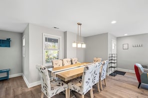 A dining area with a wooden table and floral-patterned chairs, a pendant light, and a window with blinds. - Pet-Friendly Family Home Near DC | Sleeps 16 (Hyattsville)