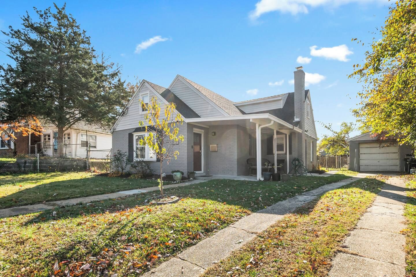A residential house with a covered porch, a visible chimney, and a well-maintained lawn.