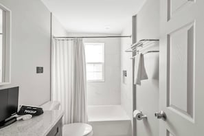A modern bathroom with a toilet, a shower, and a bathtub. There is a towel rack and a sign on the wall. - Pet-Friendly Family Home Near DC | Sleeps 16 (Hyattsville)