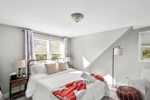 A bedroom with a bed, bedside table, lamp, window with curtains, and a floor lamp. - Pet-Friendly Family Home Near DC | Sleeps 16 (Hyattsville)