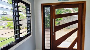 Una puerta con marco de madera y un ventanal con barrotes horizontales.
