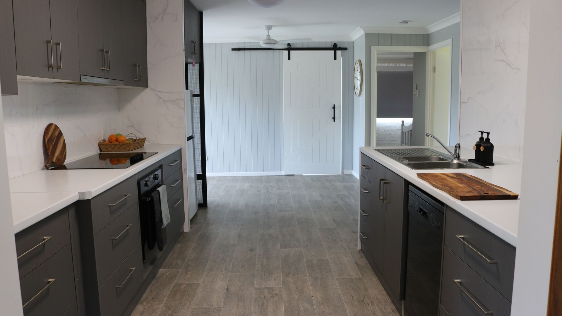 Une cuisine moderne avec des meubles de couleur gris foncé, un plan de travail blanc et une planche à découper en bois.