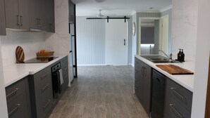 Una cocina moderna con armarios gris oscuro, encimeras blancas y una tabla de cortar de madera.