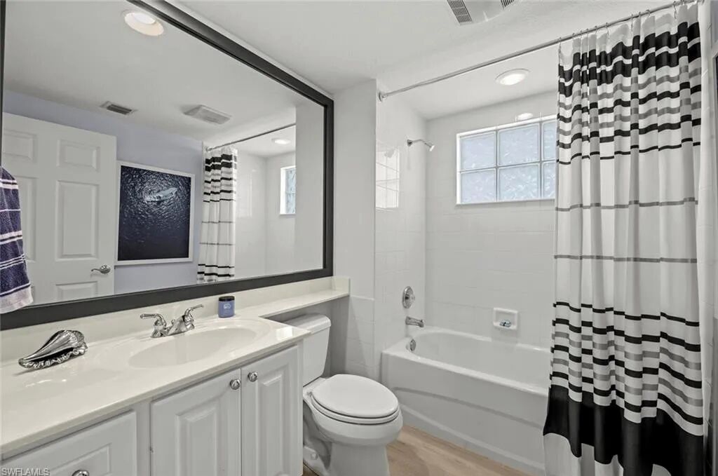A modern bathroom with a large mirror, a bathtub, and a shower curtain.