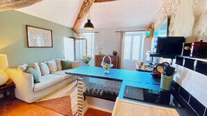 Ein gemütliches Wohnzimmer mit einer Couch, einem Couchtisch und einer Küchenzeile mit Herd und Schränken.