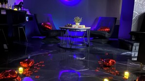 A room with a circular wall decoration, a table with a plant, and chairs. - Love room L'écrin d'Astéria (Laudun-l'Ardoise)