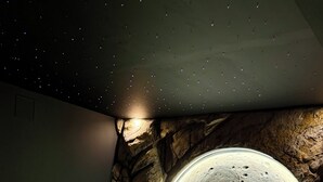 A bedroom with a bed, a large circular window, and a bathtub with green lighting. - Love room L'écrin d'Astéria (Laudun-l'Ardoise)