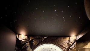 A bedroom with a bed centered under a circular ceiling feature resembling a moon, with a starry night sky effect. - Love room L'écrin d'Astéria (Laudun-l'Ardoise)
