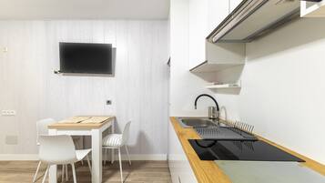 Una cocina moderna con una mesa de madera, sillas blancas, una encimera negra y una estufa empotrada.