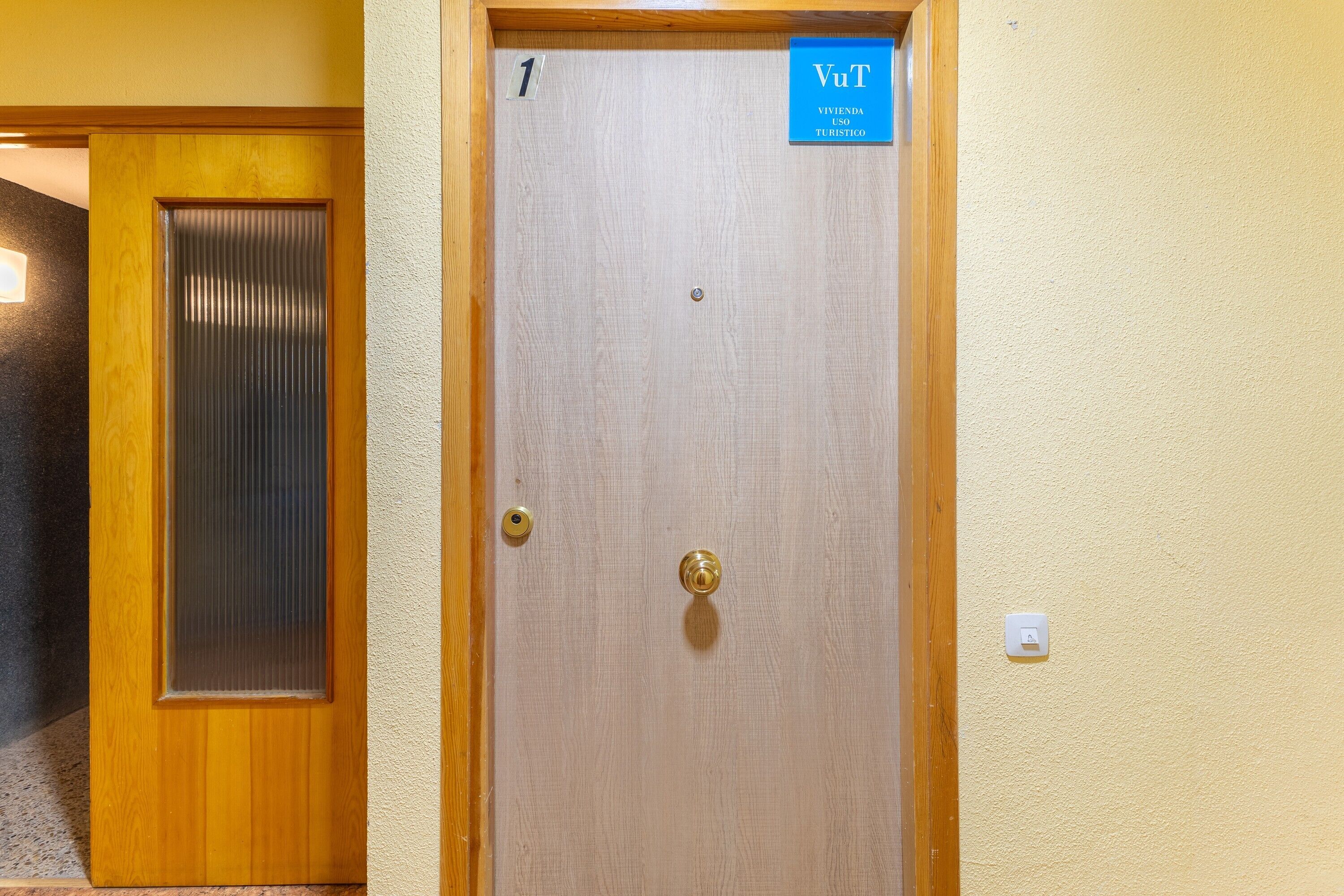 Eine Holztür mit gefrostetem Glasfenster, einer Messingklinke und einem blauen Schild, das einen Raum für Touristen kennzeichnet.