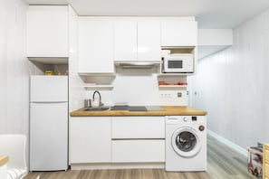 A compact kitchen with a refrigerator, microwave, sink, and washing machine. - Loft in La Pinilla, Direct Ski Slope Access and Mountain Views (La Pinilla)