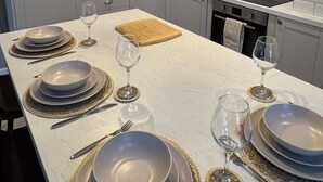 Cozinha moderna com armários brancos, ilha central com espaço para refeições e iluminação pendente.