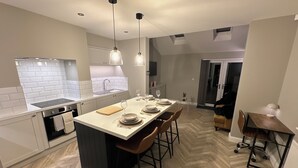 Cozinha moderna com ilha central, banquetas e iluminação pendente.
