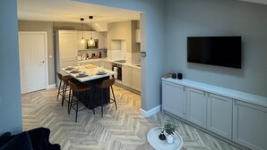 Um interior moderno com área de refeições, cozinha e TV fixada na parede.