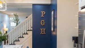 A modern kitchen with a dark blue accent wall, marble countertops, and a staircase leading to another level. - Rooftop Deck | 3 King Suites | Soaker Tub (Pittsburgh)