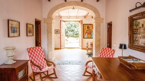 A spacious room with a high ceiling, a wooden dining table, two rocking chairs, and a large painting on the wall. - Beautiful home in Manacor with private swimming pool, can be inside or outside (Manacor)