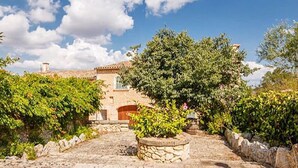 A stone pathway leading to a rustic building with a tiled roof, surrounded by lush greenery and a clear sky. - Beautiful home in Manacor with private swimming pool, can be inside or outside (Manacor)