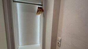 A narrow hallway with a door leading to a room. The hallway has a tiled floor and a light switch on the wall. - WhatsApp  (Barcelona)