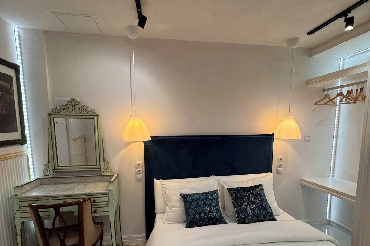 A bedroom with a bed, a desk, and two wall-mounted lamps.