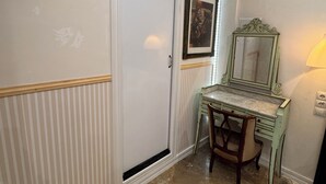 A room with a closed door, a framed picture on the wall, a vintage-style desk with a chair, and a mirror. - WhatsApp  (Barcelona)