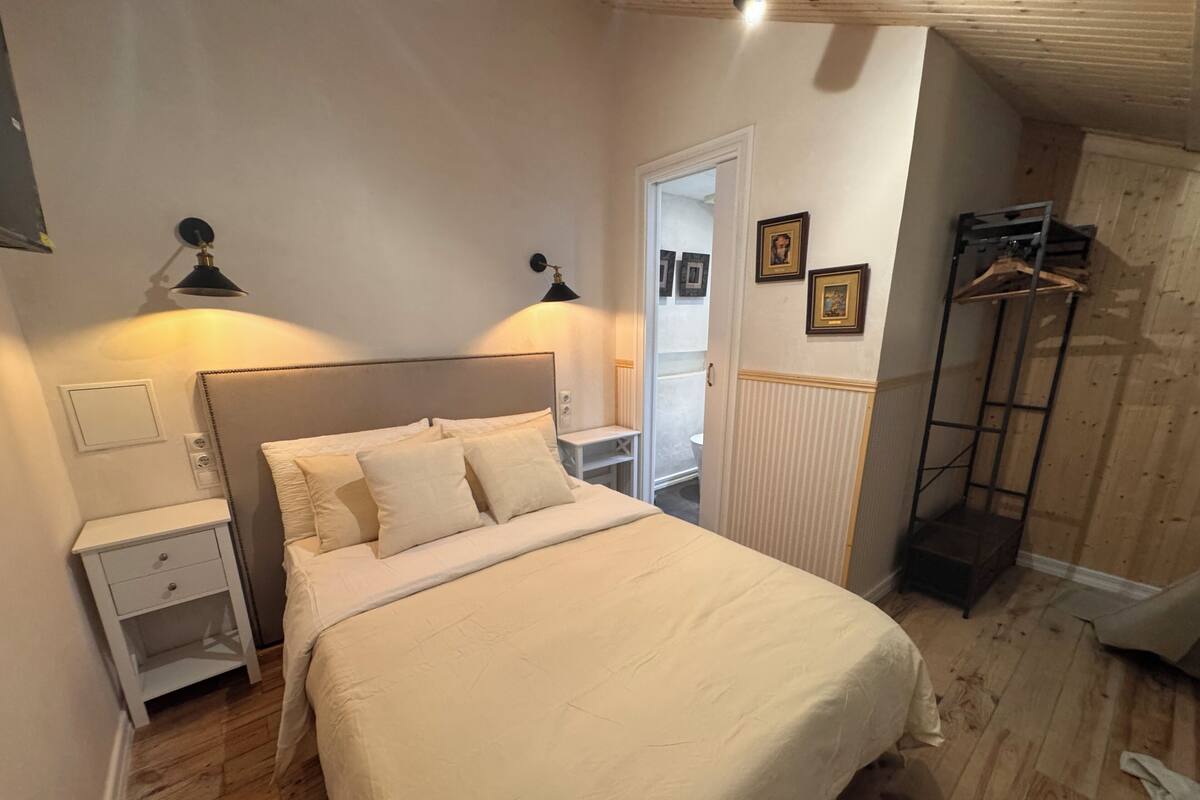 A bedroom with a bed, bedside tables, a wardrobe, and a mirror.