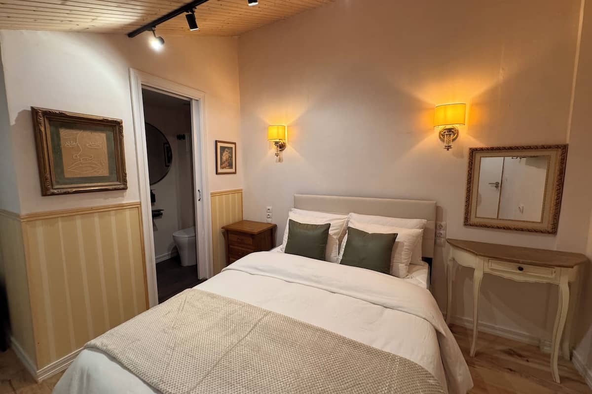 A bedroom with a bed, bedside tables, a mirror, and wall-mounted lights.