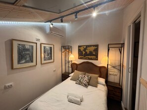 Hotelkamer met een bed, twee foto's in lijsten, een wereldkaart en een lamp.