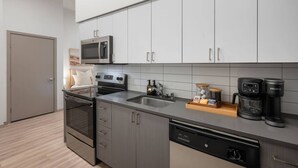 A modern kitchen with stainless steel appliances, a dishwasher, and a coffee maker. - Roosevelt Suite| Walk to Light Rail + Rooftop View (Seattle)