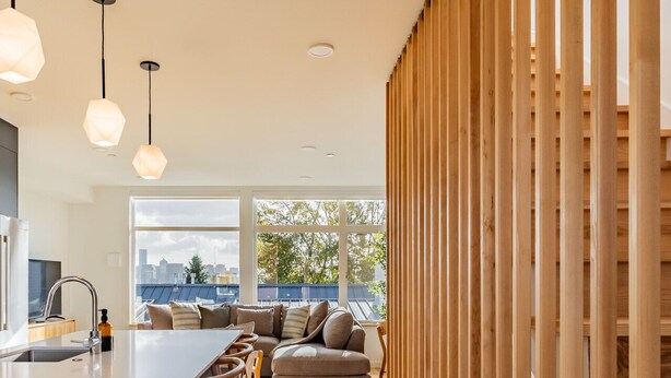 A modern kitchen with a central island, bar stools, and a large window overlooking a cityscape. - NEW Queen Anne View Retreat | Sleeps 8 w/ A/C (Seattle)