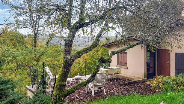 Una casa rústica con un pequeño patio, rodeada de abundante vegetación y árboles.