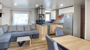 Een knus woongedeelte met een bank, een klein tafeltje en een kitchenette.