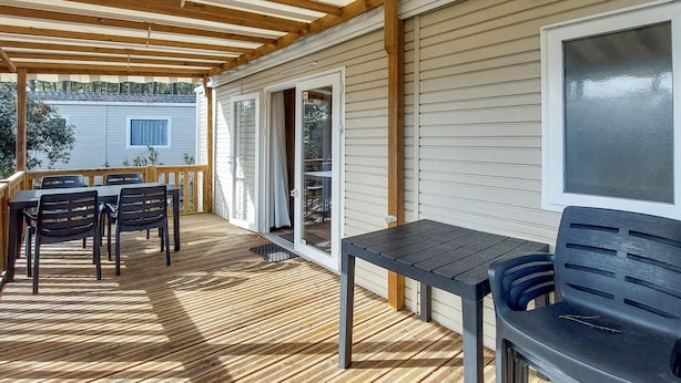 Een overdekt terras met een tafel, stoelen, een schuifpui en een raam.
