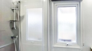Een witte deur met een matglazen raam en een douchekop aan de muur.