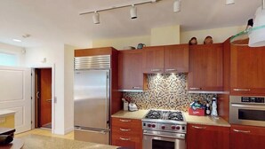 Eine moderne Küche mit Holzschränken, Edelstahlgeräten und einer gefliesten Spritzschutzwand.