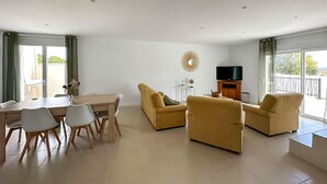 A modern living room with a dining area, a flat-screen TV, and a balcony with curtains. - Stunning home in Montignargues (Montignargues)