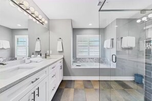 A modern bathroom with a large mirror, vanity, and a walk-in shower. - Paradise Villa- Sarasota (Sarasota)