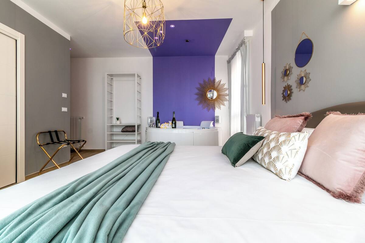A modern bedroom with a large bed, a vanity with a mirror, and a chair.