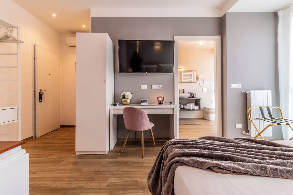 A bedroom with a bed, a desk, a chair, and a TV.
