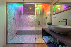 Un baño moderno con ducha envuelta en vidrio, un lavamanos grande de color blanco y un espejo sobre el lavamanos.