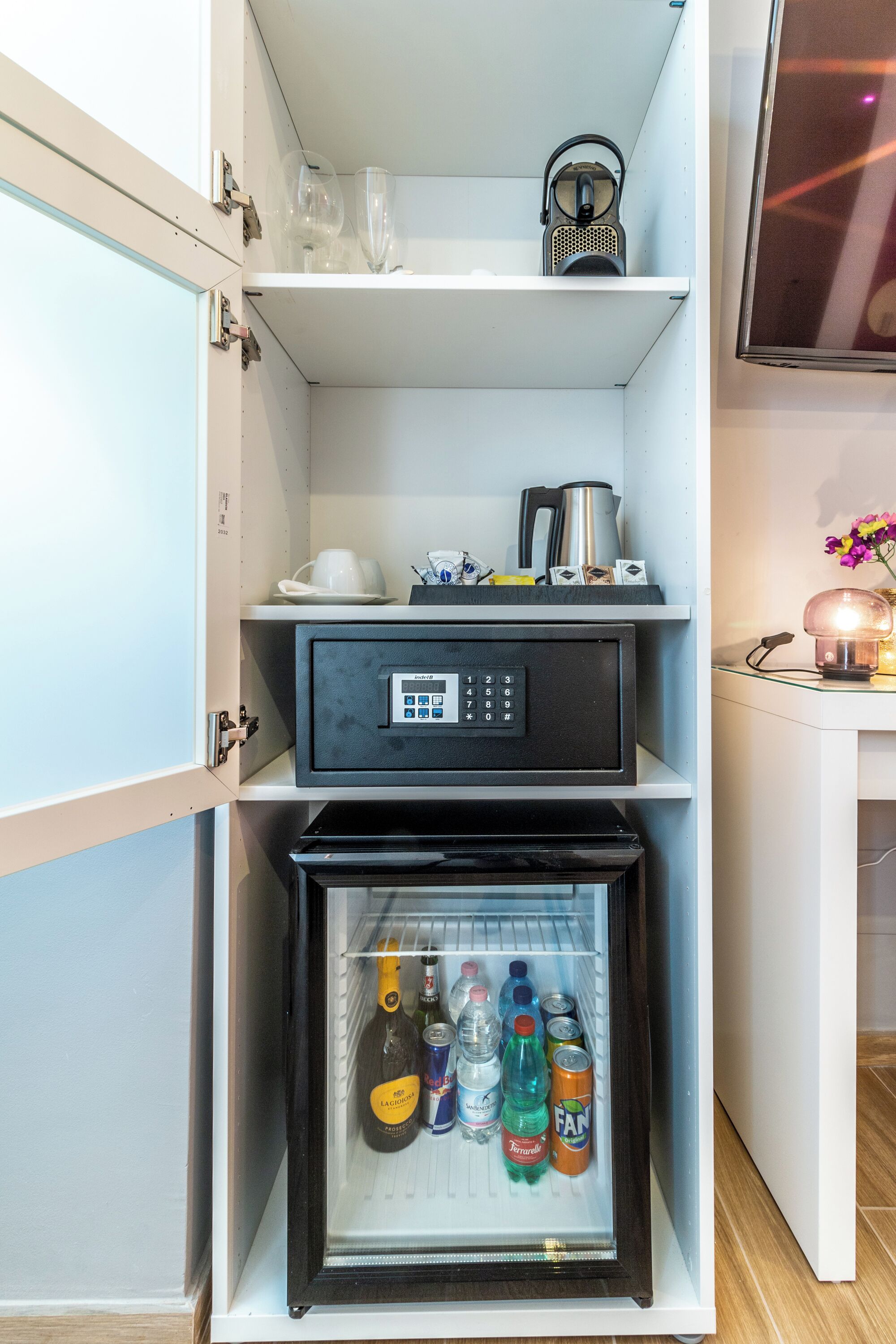 Eine kompakte Küche mit integriertem Kühlschrank, einer Kaffeemaschine und einem Wasserkocher auf der Arbeitsplatte.