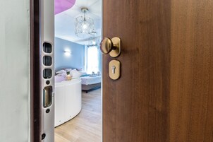 Una habitación de hotel con una puerta de madera, una encimera blanca y circular, una cama con cabecero blanco y una lámpara colgante.