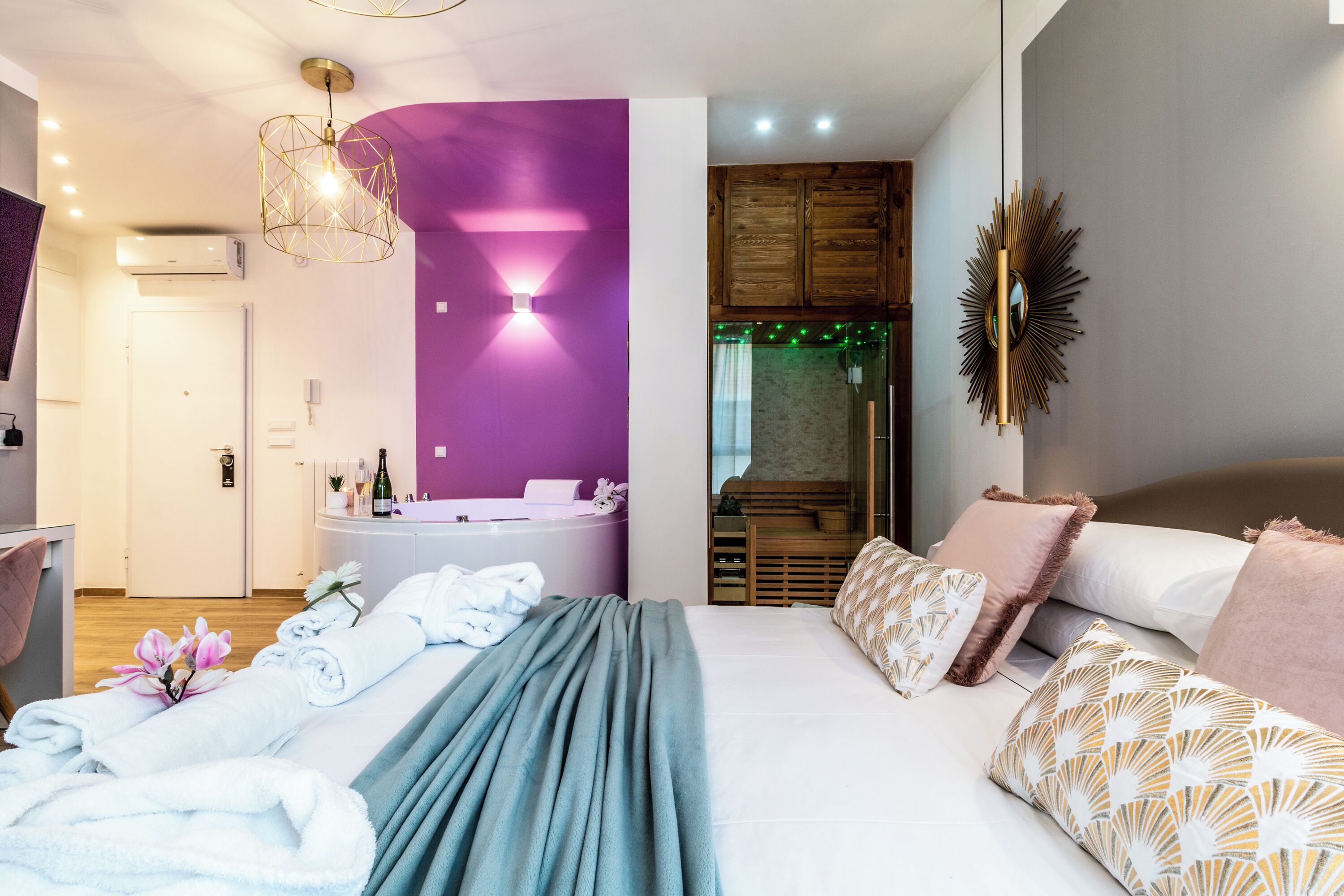 A modern hotel room with a bed, a bathroom, and a seating area.