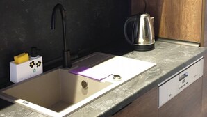Una cucina moderna con lavello in acciaio inossidabile, bollitore e lavastoviglie.