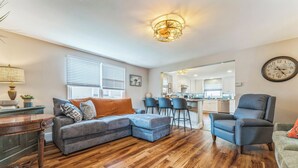 A modern living room with a sectional sofa, a wooden coffee table, and a dining area with bar stools.