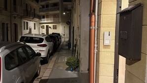Una estrecha calle urbana con coches estacionados y edificios.