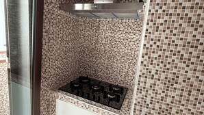 Una cocina con salpicadero de azulejos, extractor de acero inoxidable y estufa a gas integrada.