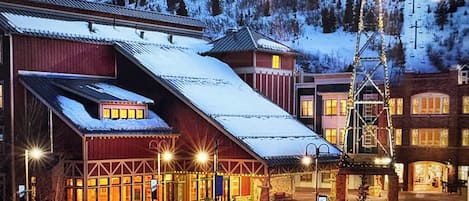Un edificio cubierto de nieve con techo inclinado, entrada de madera y un letrero que indica un restaurante.